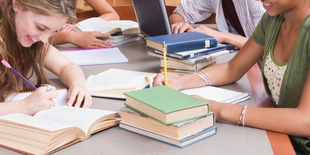 gruppo studenti al tavolo tra i libri 